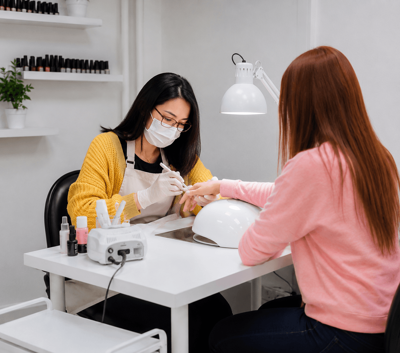 Nail technician performing nail treatment for a client at a stylish white manicure table