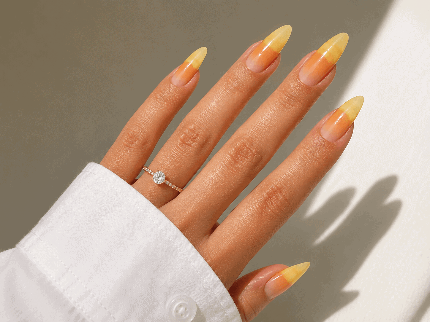 Close-up of long almond-shaped nails with a yellow and orange ombre gel nail design